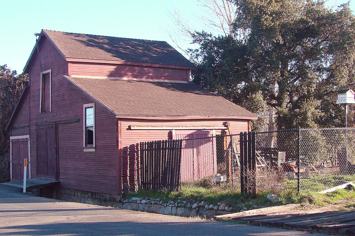 Old red wooden barn beside a road in Mentone, California